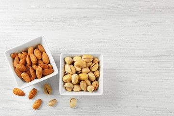 Wall Mural - Pistachios and almonds in the bowls on white wooden background