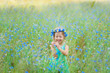 happy little girl in a field holding a bouquet of blue flowers