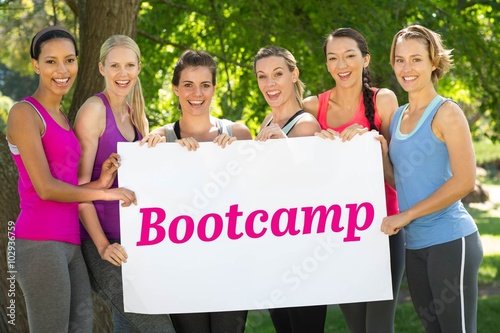 Fotografie, Obraz Bootcamp against fitness group holding poster in park