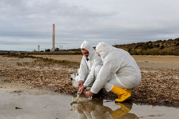 Experts Analysis Water / Two technicians levying of water samples from the river to perform the analyzes.