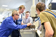 © industrieblick - Gruppe Jugendlicher bei der technischen Berufsausbildung mit Meister an einer Fräsmaschine // trainees with teacher in technical education at a milling machine