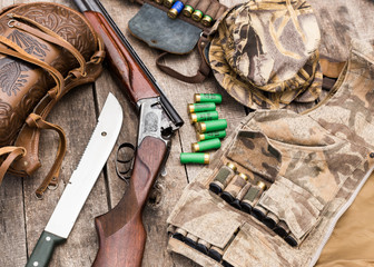 Hunting shotgun and ammunition on wooden background