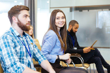 Wall Mural - Smiling young woman sitting with colleagues on business meeting