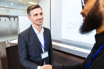 Poster - Happy businessman shaking hands with young colleague