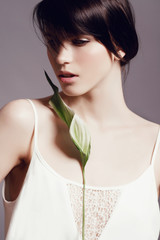 Portrait of a beautiful young brunette woman with a green leaf in the studio, the concept of beauty and health