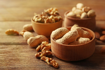 Wall Mural - Pistachios, almonds, peanuts and walnut kernels in the wooden bowls on the table, close-up