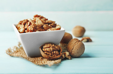 Wall Mural - Walnuts in the bowl on blue wooden background