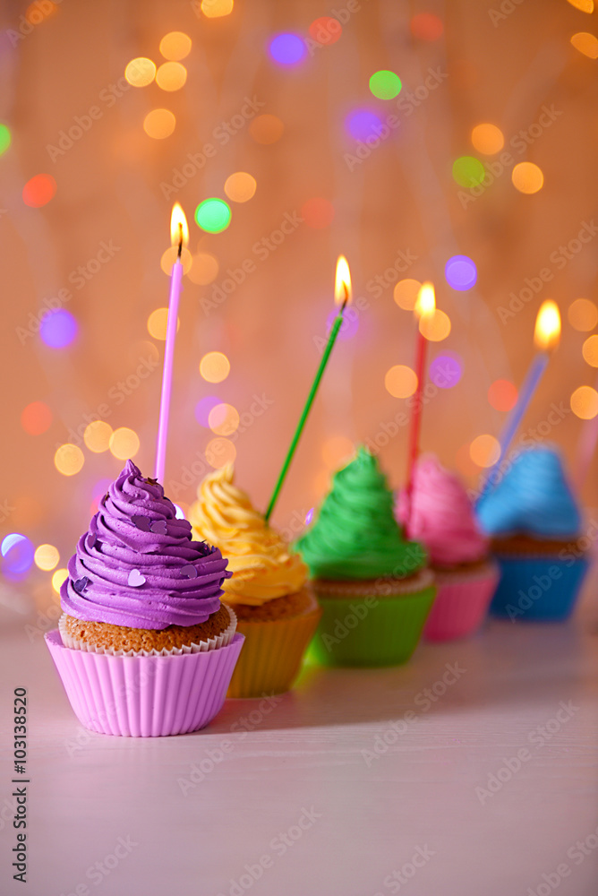 Cupcake with purple cream icing and candle on a glitter background