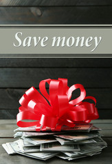 Wall Mural - Pile of dollars with bow as gift on wooden background