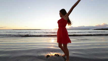 Wall Mural - Beach woman having fun spinning around dancing at sunset enjoying freedom during summer holidays vacation travel. Beautiful happy young mixed race Asian Caucasian female model outside.