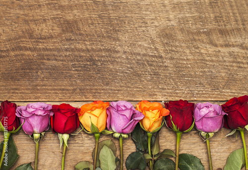 Fototapeta na wymiar Colorful roses on wooden background