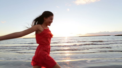 Wall Mural - Asian woman happy walking on beach at sunset cheerful and jumping full of joy. Fresh free girl enjoying summer beach in sundress during vacation holiday travel. Mixed race Asian Caucasian model.