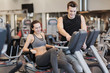 © Syda Productions - happy woman with trainer on exercise bike in gym