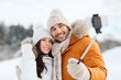 © Syda Productions - happy couple taking selfie by smartphone in winter