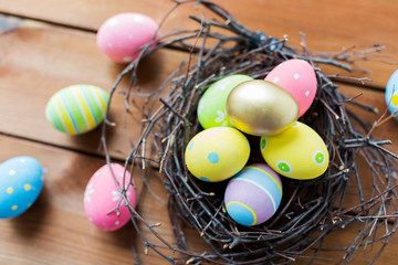 close up of colored easter eggs in nest on wood