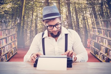 Composite image of hipster wearing eye glasses and hat working