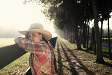 Cowgirl Woman In Cowboy Hat Flannel Shirt And Jeans Leaning On Country Rural Fence Looking Confident Happy Serene Smart Alone Waiting Watching Patient