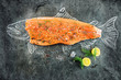 raw salmon fish steak with ingredients like lemon, pepper, sea salt and dill on black board, sketched image with chalk of salmon fish with steak