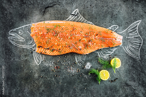 Fototapeta na wymiar raw salmon fish steak with ingredients like lemon, pepper, sea salt and dill on black board, sketched image with chalk of salmon fish with steak