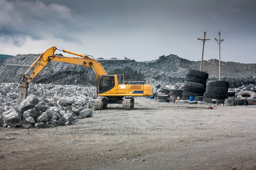 Heavy excavator with shovel standing on hill with rocks