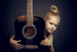 Beautiful blond young girl hug a guitar