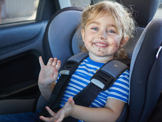 Little dirty girl , baby in a safety car seat.