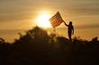 © Avarand/ADDICTIVE STOCK - Man Holding a USA Flag on a Hill