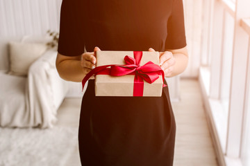 The beautiful girl holds a gift or a surprise in hand