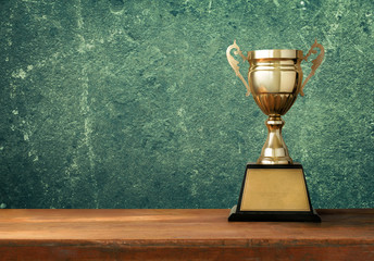 champion golden trophy on wood table with blackboard copy space