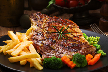 Grilled beef steak served with French fries and vegetables on a