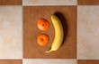 Смайлик на кафельной плитке выложенный из банана и корочек апельсинов