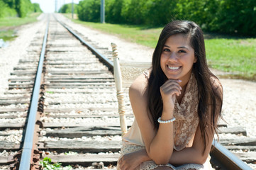 beautiful senior girl sitting on train tracks.