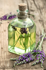 Canvas Print - Lavender oil with fresh flowers on wooden background