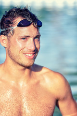 Poster - Athlete swimmer in swimming pool with swim goggles. Handsome young professional male sports adult portrait looking happy after cardio workout exercising in outdoor water, topless wearing swimwear.