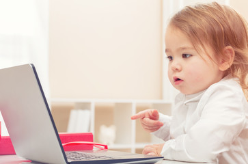 Wall Mural - Happy toddler girl on her laptop