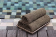 Three grey towels rolled near swimming pool