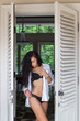 Beautiful woman with long black hair posing near white door