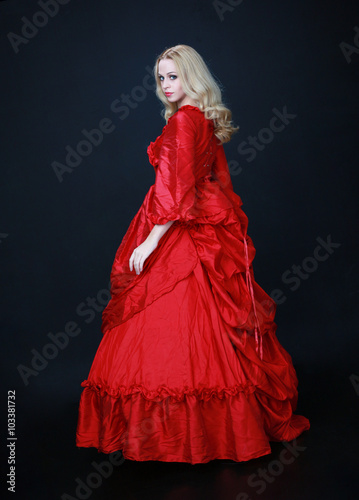 Foto full length portrait of a beautiful blonde woman wearing a historical red silk, victorian era ball gown