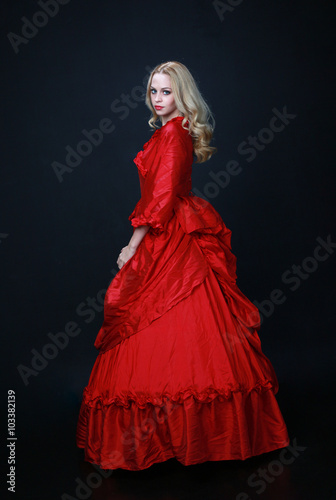 full length portrait of a beautiful blonde woman wearing a historical red silk, victorian era ball gown Canvas