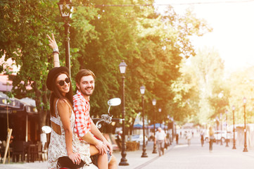 young couple riding  a vintage scooter in the street