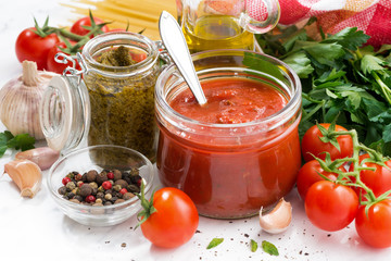 Wall Mural - tomato sauce, pesto and ingredients for pasta on a white table