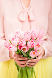 Fototapeta Tulipany - Bunch of tulips in woman's hands, shallow dof.