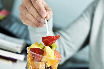 youn man eating a fruit salad at the office