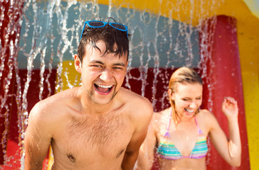 Canvas Print - Couple in swimmning suits under splashing fountain. Summer heat.