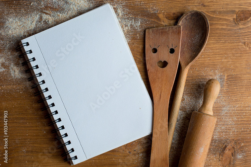 Fotografía Open recipe book with wooden spoon, rolling pan and spatula