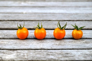 Four yellow Sungold cherry tomatoes on a wooden table 