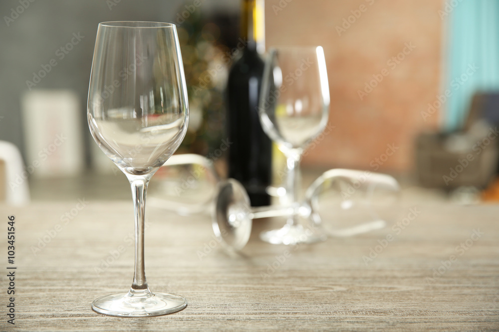 Empty wine glasses with bottle on wooden table against blurred background
