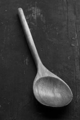 wooden kitchen spoon on an old black table, closeup, selective focus. rustic style. black and white photo