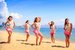 © SlavaStock - cheerleaders stand on beach hold hands on hip against azure sea