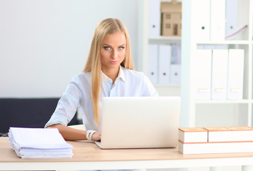 Attractive businesswoman sitting on a desk with laptop in the office